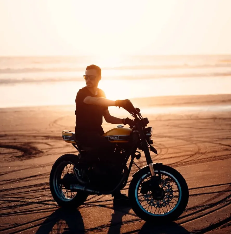 Jon with a motorcycle on a beach at sunset